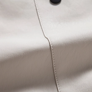 Close-up of cream leather jacket showing litchi texture, fine stitching and black button