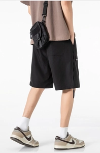 Detail of black cargo shorts with functional side zippers and adjustable straps