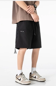Detail view of black cargo shorts with elastic drawstring waist and side button pockets