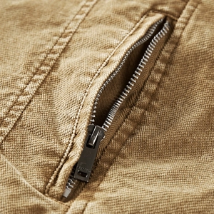 Close-up of durable khaki cotton denim jacket showing side pocket with metal zipper detail