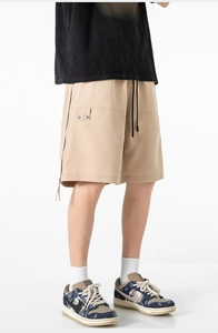 Detail of khaki cargo shorts with side pocket, metal buckle, and black drawstrings