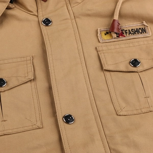 Close-up of khaki hooded jacket showing cotton twill fabric texture and T FASHION patch