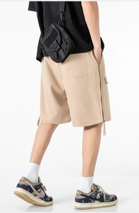 Detail view of khaki cargo shorts with side zipper accents and rear pocket design