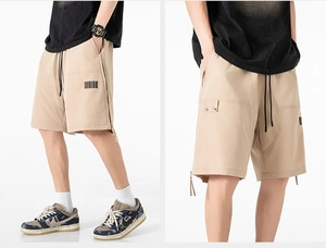 Detail view of khaki cargo shorts featuring functional large side pockets and barcode print