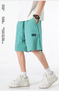 Detail of mint green cargo shorts with barcode print and black drawstring waist