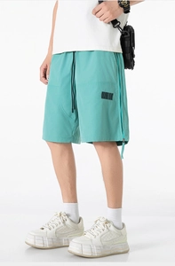 Detail of mint green cargo shorts with barcode print, side zipper, and black drawstring