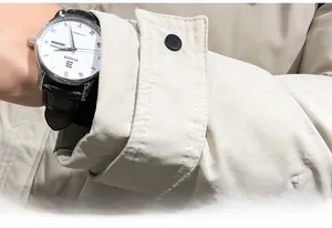 Detail of beige jacket cuff with fine stitching and black decorative adjustment button