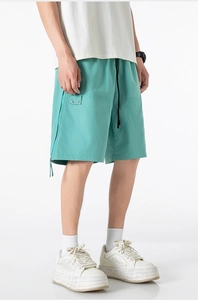 Detail of mint green cargo shorts with utility pockets and metal buckle hardware