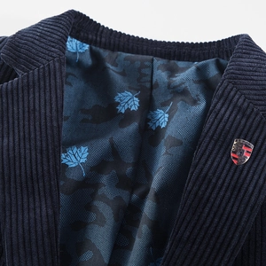 Detailed close-up of navy corduroy blazer featuring a metal crest pin and floral lining