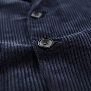 Detailed macro view of dark blue corduroy fabric texture and premium black buttons on blazer