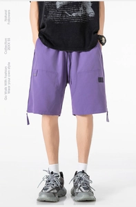Detail view of purple tactical shorts featuring large utility pockets and zipper ribbons