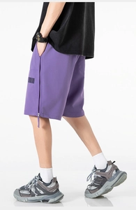 Detail view of purple cargo shorts featuring a vertical side zipper and barcode print detail
