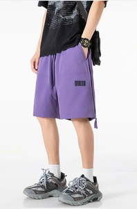 Detail view of purple streetwear shorts featuring side zipper vents and barcode print