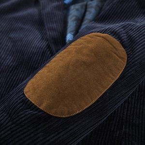 Detail of dark blue corduroy jacket sleeve with brown suede oval elbow patches