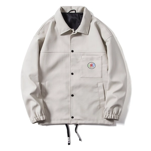 Close-up of cream faux leather jacket with snap buttons and a branded SMO logo patch