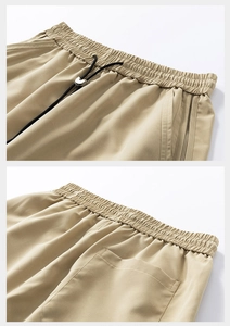 Detail of khaki functional shorts featuring elastic waist, black drawstring and metal toggle