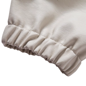 Macro shot of elastic cuffs on a white PU leather jacket showing detailed grain texture