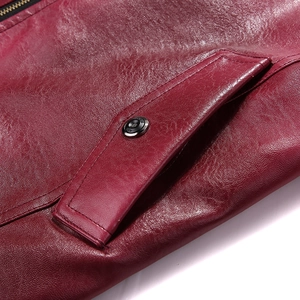 Macro view of dark red leather jacket pocket featuring metal snap buttons and zipper detail