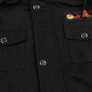 Detail of black military jacket featuring dual chest pockets and embroidered patch