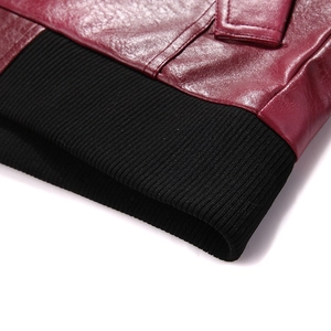Macro shot of burgundy leather jacket featuring black ribbed knit hem and detailed stitching