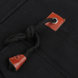 Detail of jacket drawstring with brown leather accents and metal eyelet on black fabric
