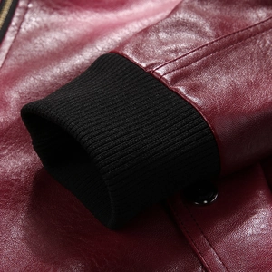Detail of burgundy leather jacket sleeve with black ribbed knit cuffs and polished button