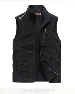 Detail of black fleece vest with zip pockets and orange pullers on a white background