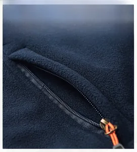 Macro detail of men's fleece vest featuring a zip pocket with orange anti-slip puller
