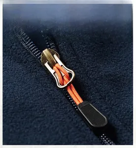 Detailed macro view of the durable metal zipper with orange pull cord on navy fleece vest