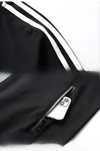 Detail of black sports jacket featuring white shoulder stripes and a secure zipper side pocket