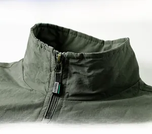 Détail du col montant avec fermeture éclair sport sur veste coupe-vent vert foncé