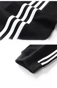Detail view of black cotton sports pants with white side stripes and ribbed cuffs