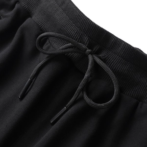 Close-up of black cotton tracksuit bottoms featuring elastic ribbed waistband and drawstrings