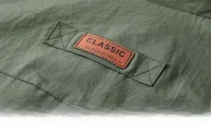 Gros plan détaillé du gilet vert armée avec étiquette en similicuir marron et relief classique