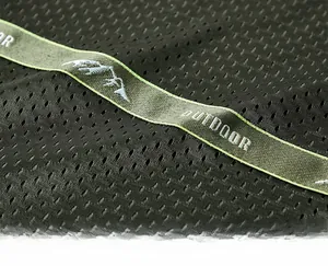 Détail du tissu en maille verte avec logo outdoor et finitions des coutures intérieures