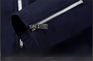 Detail view of a navy blue jacket cuff featuring a premium silver metal zipper design