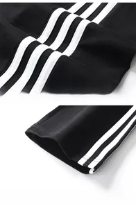 Vue détaillée du pantalon de sport noir en coton avec bandes latérales blanches et ourlet
