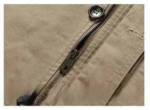 Detailed close-up of heavy-duty bronze metal zipper and buttons on khaki cotton jacket