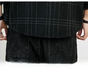 Detail des Saums an einem schwarz karierten Langarmhemd kombiniert mit schwarzer Jeans
