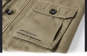 Detail of khaki men windbreaker featuring a reinforced flap pocket and black button closure