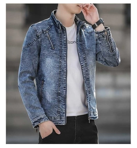 Detail of vintage washed blue denim jacket featuring zipper pockets and stand collar
