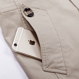 Dettaglio della tasca di una giacca in twill di cotone kaki con bottone marrone scuro