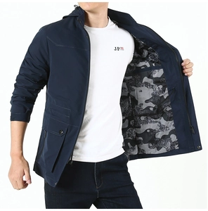Close-up of men's dark blue windbreaker featuring a camo lining and multiple functional pockets
