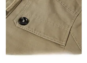 Gros plan détaillé d'une poche de veste kaki avec coutures contrastées et bouton noir