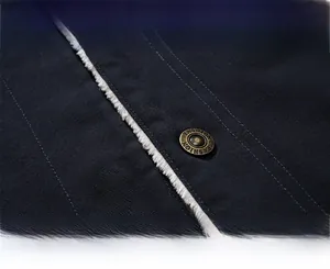 Detail of vintage bronze metal button and white fleece lining on navy winter work jacket