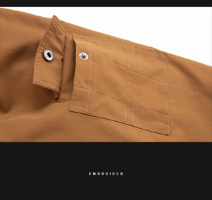 Detail of khaki jacket utility pocket with metal button and decorative stitching