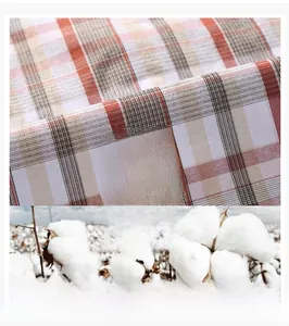Close-up of red and white plaid cotton fabric texture with a natural cotton field background