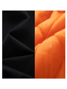 Detail of black windproof outer fabric and orange diamond quilted lining on a men's jacket
