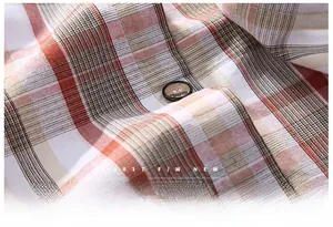 Macro shot of the plaid pattern fabric and engraved button on the men's casual shirt