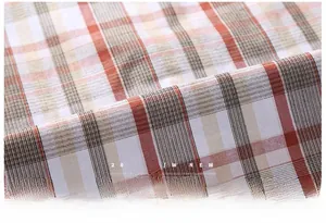 Detailed close-up of plaid fabric texture in orange and brown for men's casual shirts
